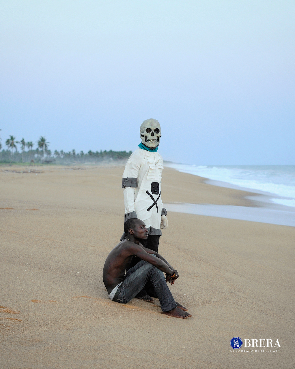 Spiaggia con un uomo in piedi con una maschera ed un uomo seduto